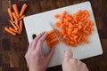 WomanÃ¢â¬â¢s hands chopping baby carrots, white cutting board on wood butcher block